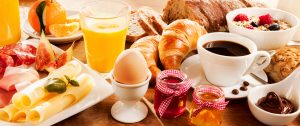 Breakfast feast with egg, meat, bread, coffee and juice